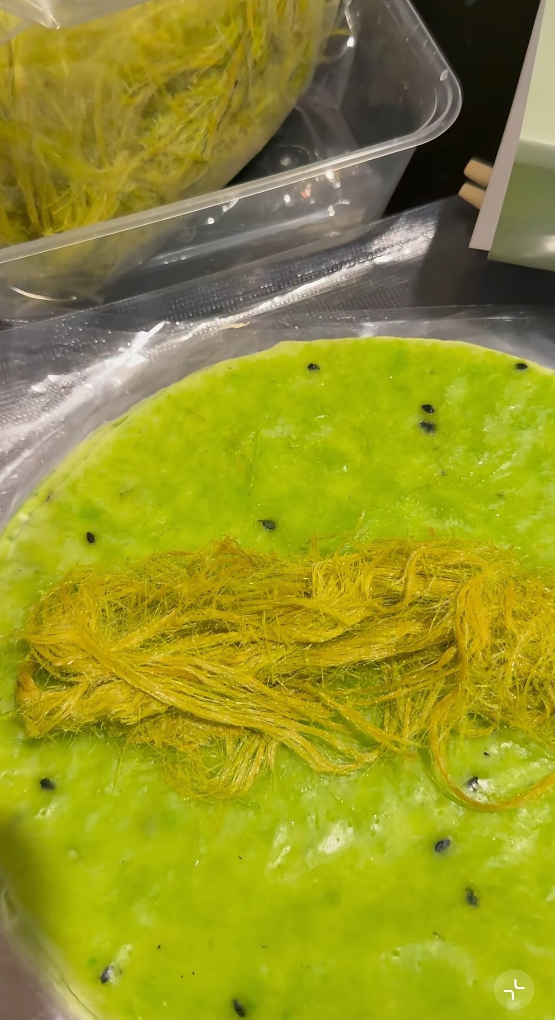 Close up of green roti sai mai being assembled.