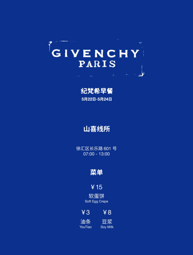 山喜线所 (Shanxi Noodle Shop)'s blue menu placard for Givenchy's 2026 Shanghai pop-up: 纪梵希早餐 (Givenchy Breakfast) offering 软蛋饼 (Soft Egg Crepe), 油条 (YouTiao / Deep-Fried Dough Stick), and 豆浆 (Soy Milk)
