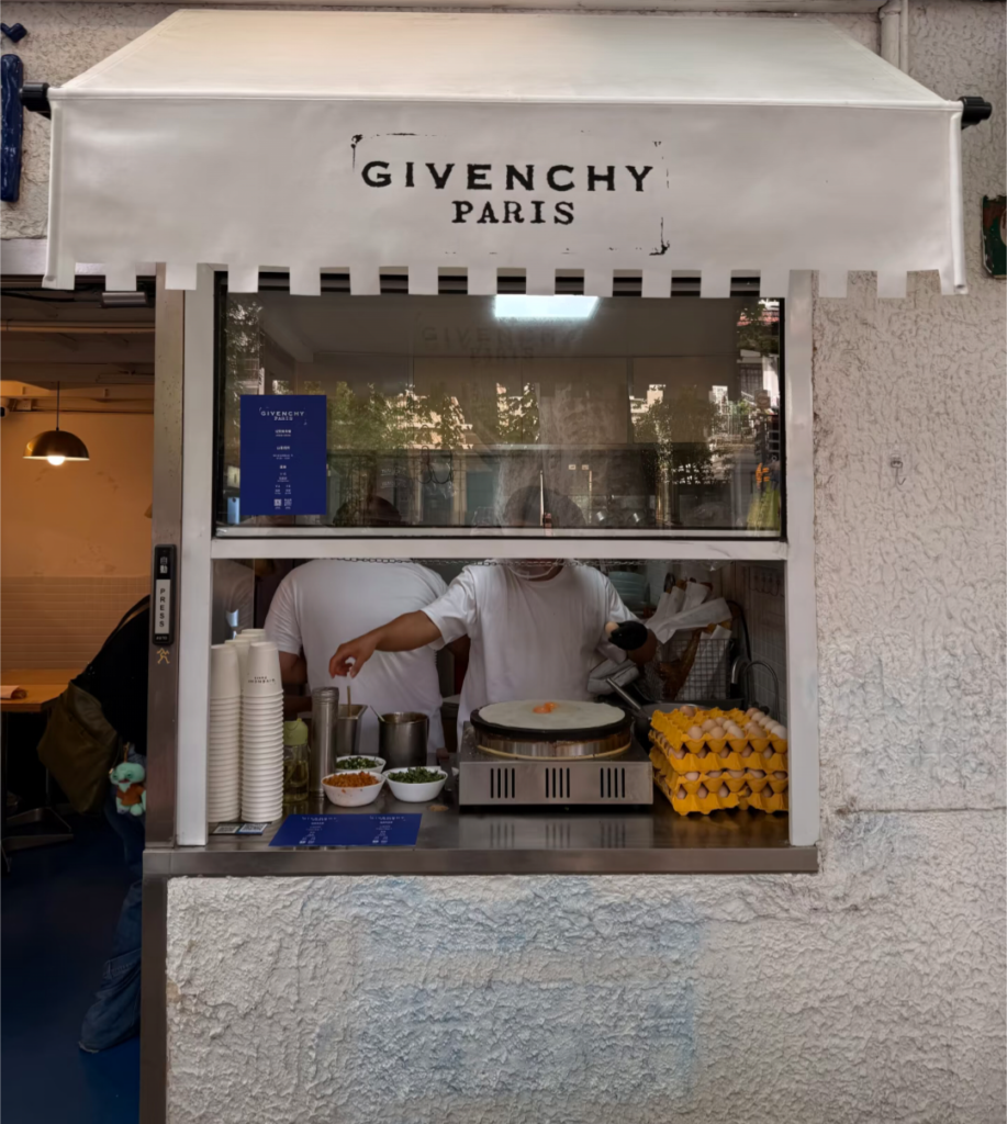 Givenchy's 2026 Shanghai pop-up: 纪梵希早餐 (Givenchy Breakfast) - 山喜线所 (Shanxi Noodle Shop) storefront serving 软蛋饼 (Soft Egg Crepe), 油条 (YouTiao / Deep-Fried Dough Stick), and 豆浆 (Soy Milk)