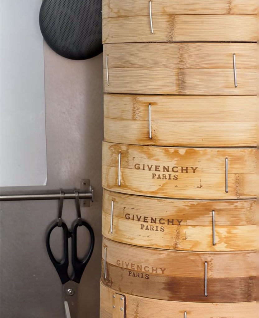 Givenchy's 2026 Shanghai pop-up: 纪梵希早餐 (Givenchy Breakfast) at 山喜线所 (Shanxi Noodle Shop) carrying multiple 小笼包 (XiaoLongBao / Soup Dumplings) steamer baskets